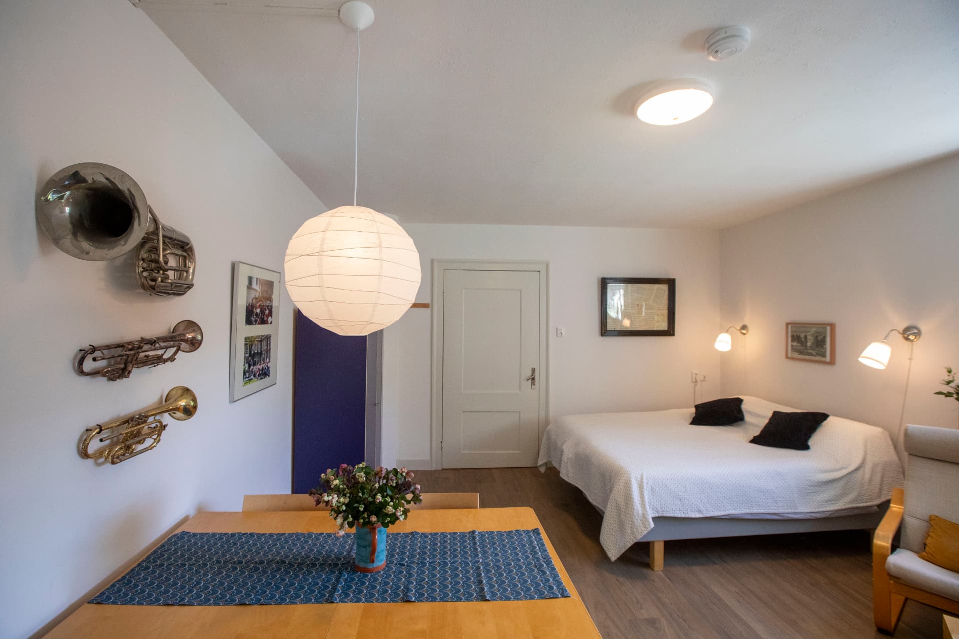 Licht appartement met tweepersoonsbed, eettafel en muziekinstrumenten aan de wand