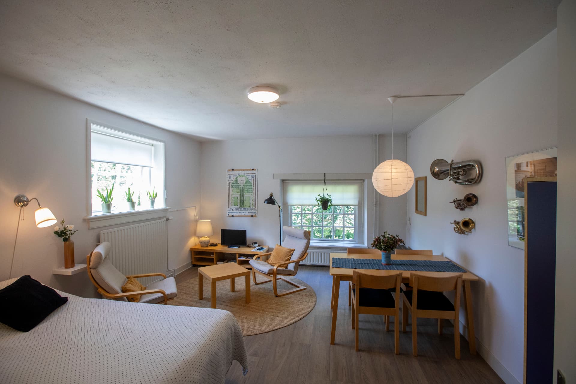 Licht ingerichte logeerkamer met zithoek, eettafel en uitzicht op het groen