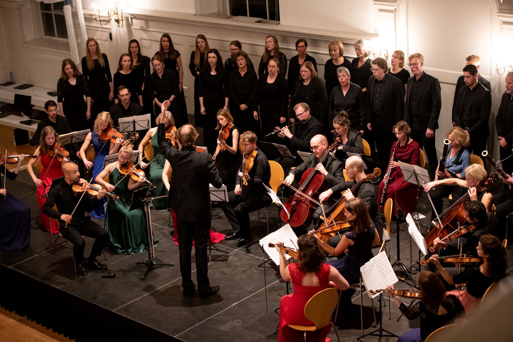 Koor en orkest voeren onder leiding van een dirigent de Matthäus-Passion uit in de Grote Kerkzaal